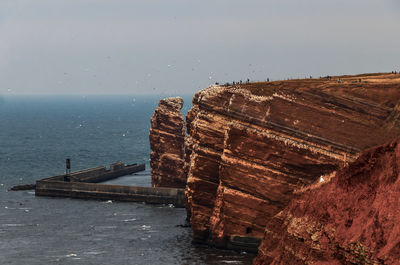 Scenic view of sea by mountain against sky