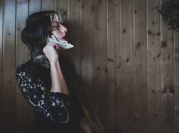 Side view of young woman standing against wall