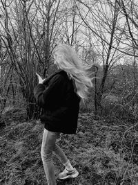 Midsection of woman standing by bare tree on field