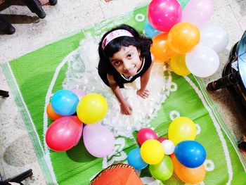 Girl playing with colouful balloons, happy looking at camera