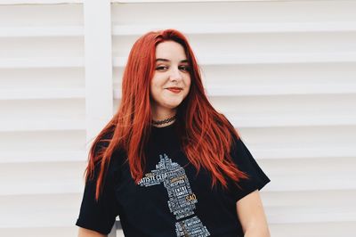 Portrait of beautiful young woman standing against wall