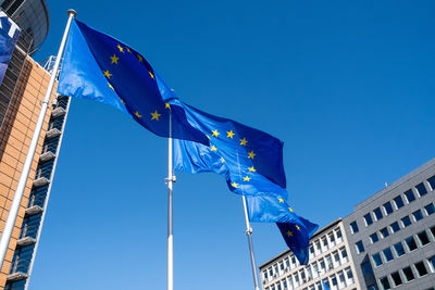 Low angle view of flag against buildings against blue sky