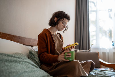 Introverted teenage girl spending sunny weekend at home, scrolling social networks, news in internet