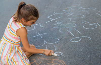 Girl doing mathematics with chalk on sidewalk