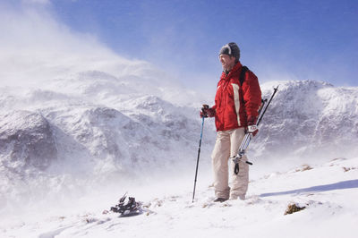 Man standing on snowcapped mountain against sky