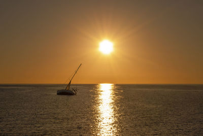 Silhouette sailboat in sea against sky during sunset