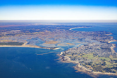 Aerial view of city by sea against sky