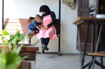 Mother with son sitting on bench in city