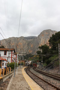 Railroad tracks by mountain against sky