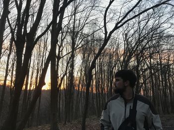 Full length of teenage girl standing in forest during sunset