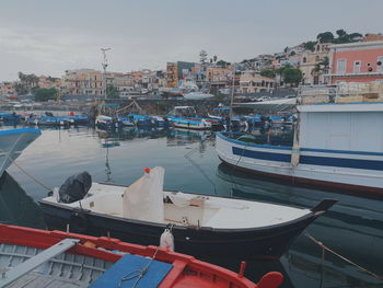 Boats moored in harbor against buildings in city