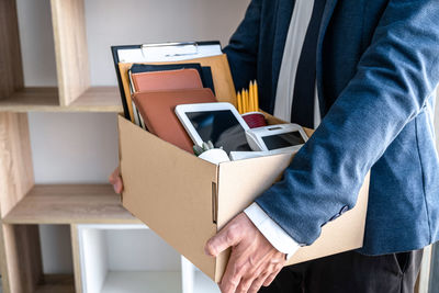 Midsection of man holding mobile phone in box