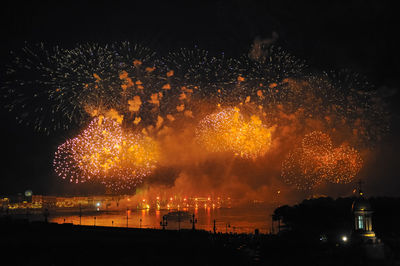 Firework display over lake at night during scarlet sails