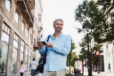 Portrait of smiling young man standing in city