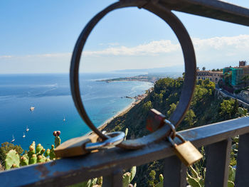 Close-up of metal fence by sea against sky