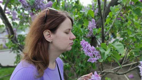 Portrait of young woman against purple flowering plants