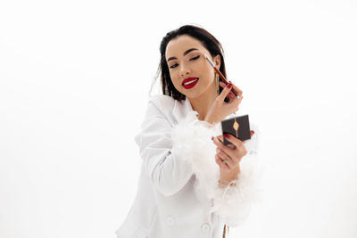 Portrait of a beautiful girl applying a makeup on a white background