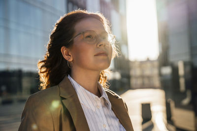 Smiling businesswoman day dreaming on sunny day