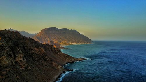 Scenic view of sea and rocks against clear sky