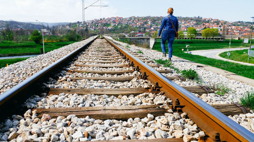 Rear view of woman walking by railroad track
