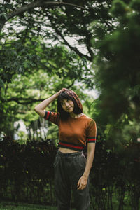 Thoughtful young woman looking away while standing against trees in park