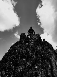 Low angle view of man standing on cliff against sky