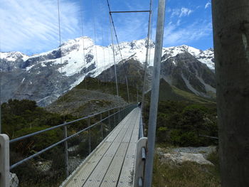 Snow covered footbridge against sky