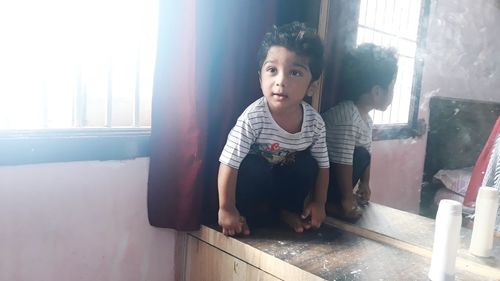 Portrait of girl looking through window at home