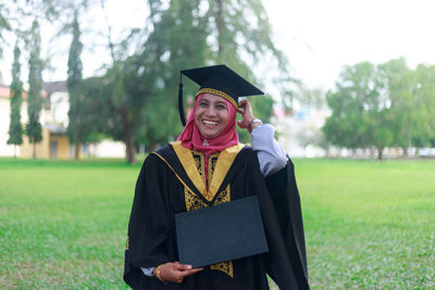 Portrait of happy woman holding placard on field