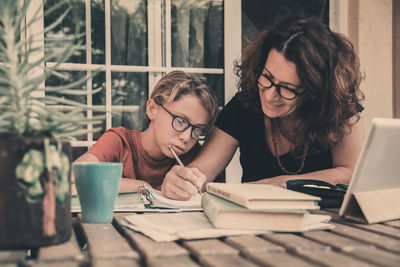 Mother helping boy in study at home