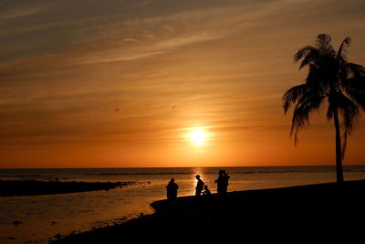 Silhouette people on beach during sunset