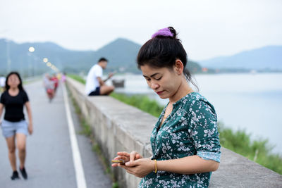 Beautiful happy woman using phone by lake