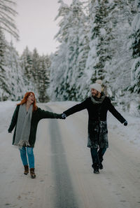 Full length of woman standing on snow covered tree