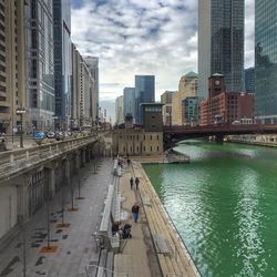 View of city at waterfront against cloudy sky