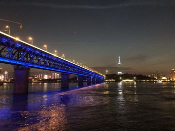 Illuminated bridge over river at night