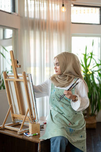 Side view of young woman using laptop while sitting at home