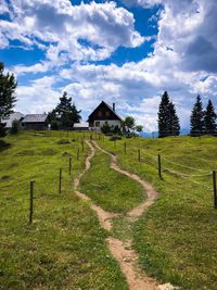 Scenic view of field by houses against sky