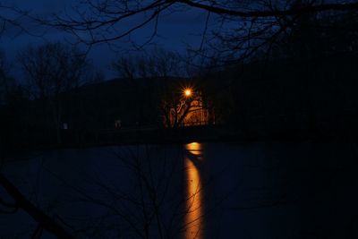 Reflection of bare trees in river at sunset