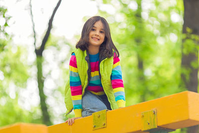 Portrait of a cute smiling little girl, in a multi-colored striped jumper and a green vest