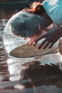 Close-up of woman wearing glass container at lake