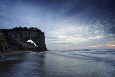 Rock formation on sea against sky during sunset