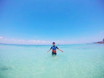 Portrait of man standing in sea against blue sky