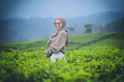 Portrait of young woman standing on field