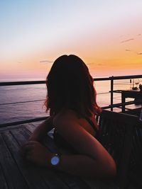 Woman looking at sea against sky during sunset