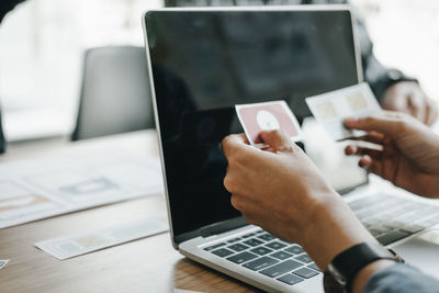 Midsection of man using laptop on table