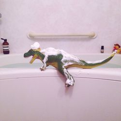 Toy dinosaur covered in foam at bathroom