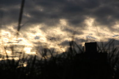 Low angle view of silhouette buildings against cloudy sky