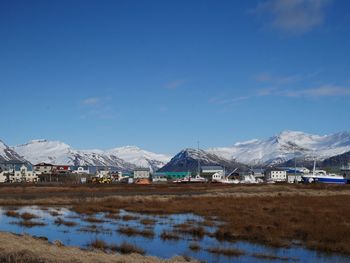 Houses on snowcapped mountain against blue sky