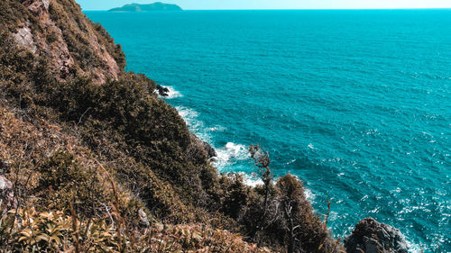 High angle view of rocks by sea against blue sky