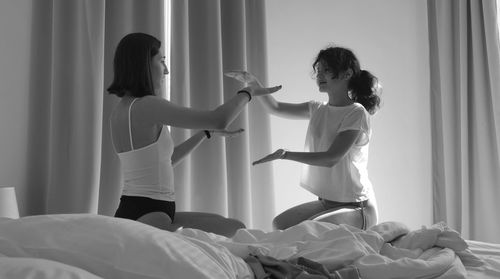 Young woman standing on bed at home